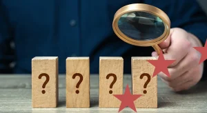 Persona osserva con lente blocchi di legno con punti interrogativi, concetto di valutazione degli interventi